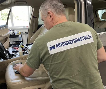 Nahaspetsialist pühib beeži nahkistet halli lapiga, nahkistmetega autole soovitame suvel tuuleklaasi taha päikesevarju, sest otsene päike kuivatab istmepatja.